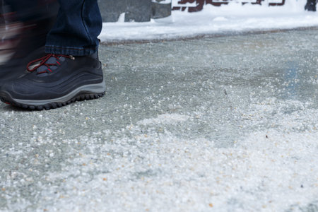 Pedestrian's foot and snow reagent on the sidewalk in winter.の写真素材
