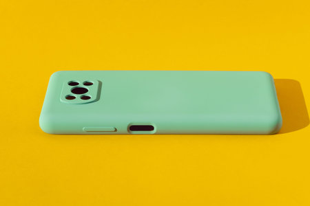 Light green silicone case for a smartphone on a yellow background, copy space.の写真素材