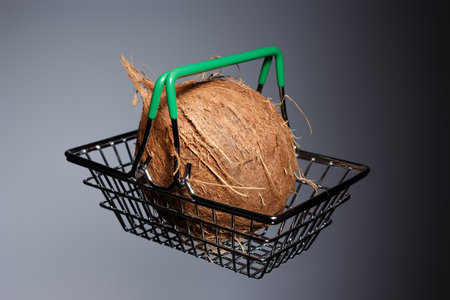 Coconut in a grocery metal basket on a gray background with a gradient.の写真素材