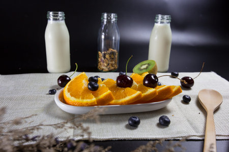healthy breakfast ingredients, homemade granola in bottle , milk  and fresh fruit , orange,...