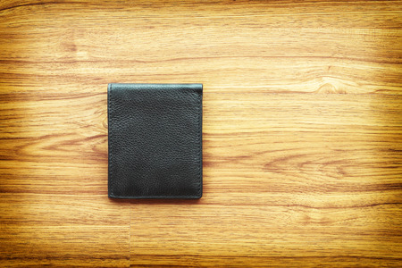 it is black leather wallet on wooden background.の写真素材