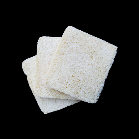 it is three pieces of gluten free white bread isolated on black.の写真素材