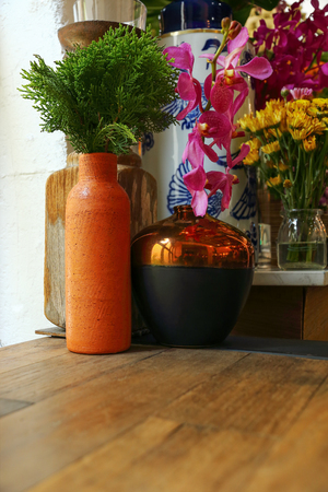it is pine tree leaf in pottery vase on wood table and flowers.の写真素材