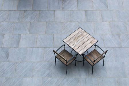 set of wooden table and two chairs on stone floor outdoor.の写真素材