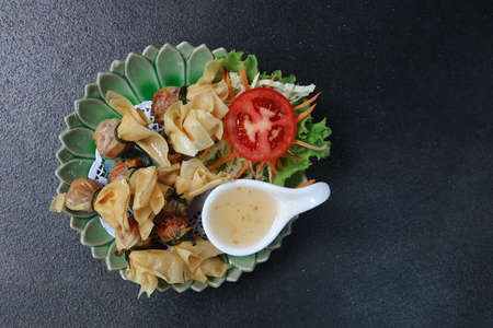fried crispy meat spring roll with plum sauce and mixed vegetable served on circle zig zag plate.の写真素材