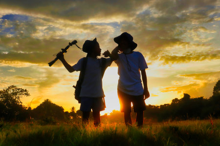 Silhouette of asian boy and girl with telescope at sunsetの写真素材