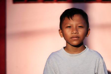 Portrait of a young asian boy in front of a wallの写真素材