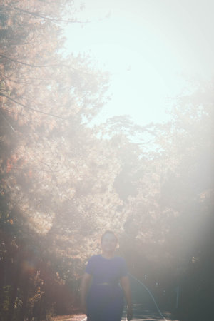 Pregnant woman walking in autumn forest. Photo in old color image style.