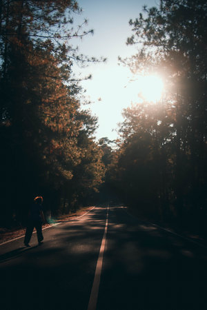 Silhouette of a woman walking on the road in the forest