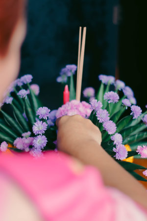 Close-up of female hands holding incense sticks and flowers.の写真素材