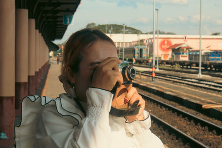 A young Asian woman is taking a picture of the railway station.の写真素材