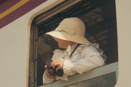 A woman in a hat and a white shirt is traveling by train.