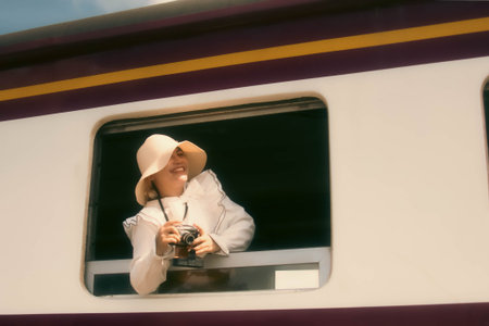 Young beautiful woman in a hat with a camera in a train windowの写真素材