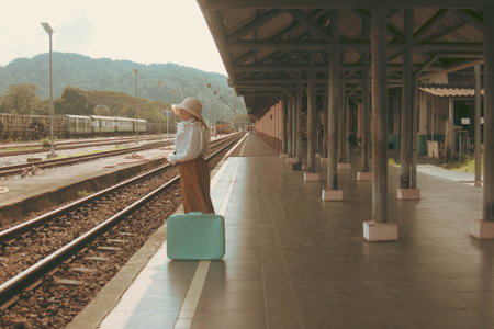 Woman traveler with suitcase waiting train at railway station. Travel concept.の写真素材