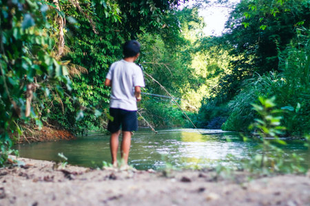 Little boy fishing in a river in the jungle. Selective focus.の写真素材