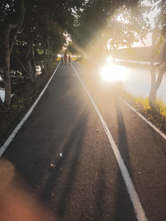 Three people are walking on a road at sunset.の写真素材
