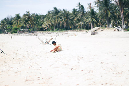 Young woman sitting on the sand of a tropical beach in Sri Lankaの写真素材