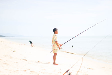 Little boy fishing on the beach with fishing rod in summer day.の写真素材