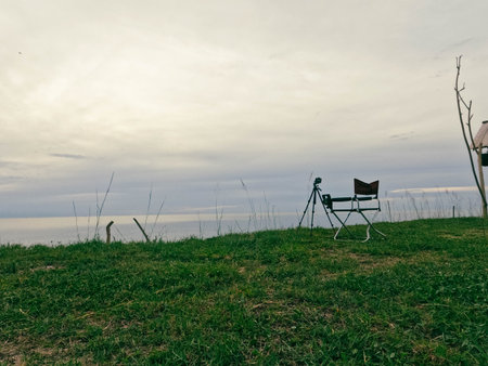 Silhouette of a chair and a camera on a green meadowの写真素材