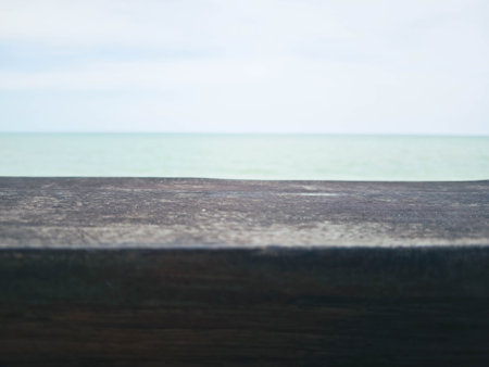 Wooden table top on blur sea and sky background - can be used for display or montage your productsの写真素材