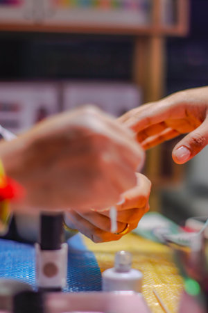 Close-up of manicurist applying nail polish on female fingers