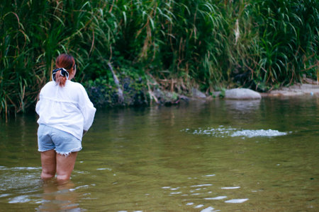 A girl in a white shirt is standing in the middle of the river.