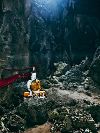 Buddha statue in the cave with red cloth, Thailand.の写真素材