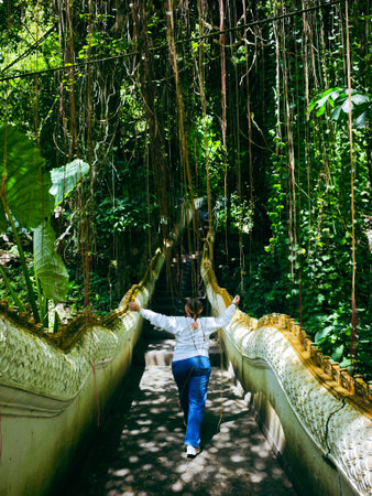 Woman walking on a suspension bridge in the jungle, Bali island, Indonesiaの写真素材