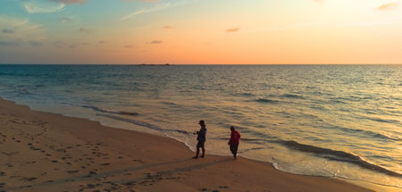 Silhouette of a mother and son walking on the beach at sunset