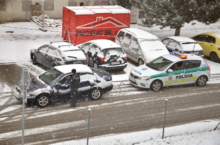 Bytca, Slovakia - February 17, 2017: Police traffic partol stop a car. Policeman stand outside vehicle in bad weather and talk with driver while snow falls.のeditorial素材