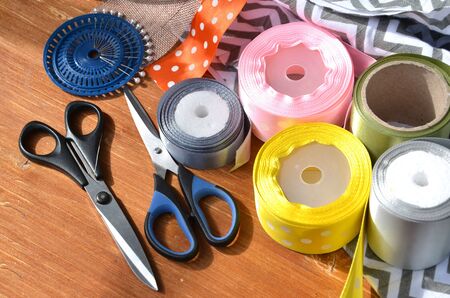 Color ribbons, scissors and pins set on wooden plankの写真素材