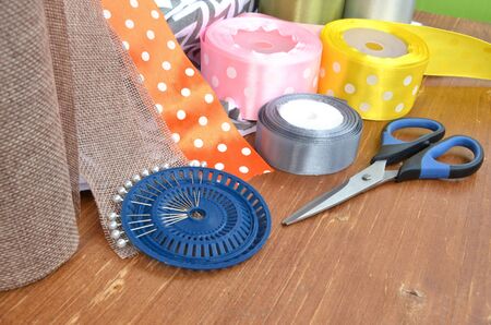 Color ribbons, scissors and pins set on wooden plankの写真素材