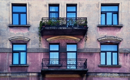 facade of an old house with metal balconies and overgrown with flowersのeditorial素材