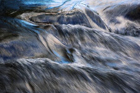 abstract background blue reflection of the sky on a flowing riverの写真素材