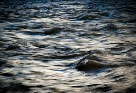 background or texture dark cold winter river with wavesの写真素材
