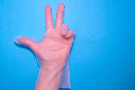 Womens hands in transparent household gloves on a blue background. Hand protection.の写真素材