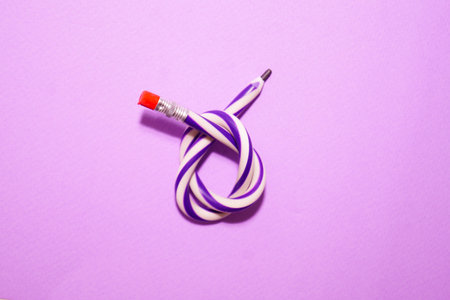 Flexible pencil on a purple background. The curved pencil is two-tone. Purple and white.