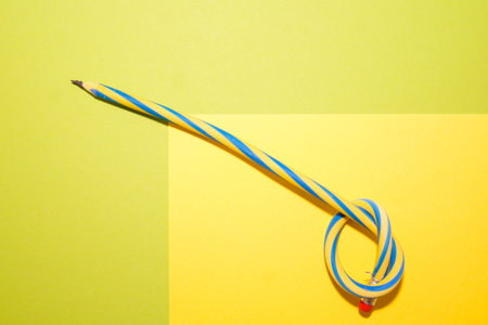 Flexible pencil on a yellow-green background. The curved pencil is two-tone. Blue and yellow.の写真素材