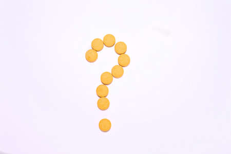 A question mark made of yellow pills. White background. Top view.の写真素材