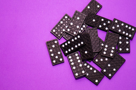 A domino of black color lies on the right half on a purple background. Space for text.の写真素材