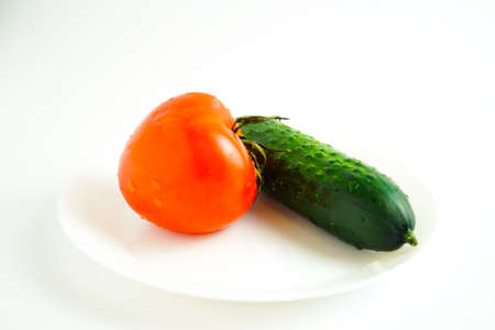 Cucumber and tomato are on a white plate. White background. The concept of healthy lifestyle.の写真素材