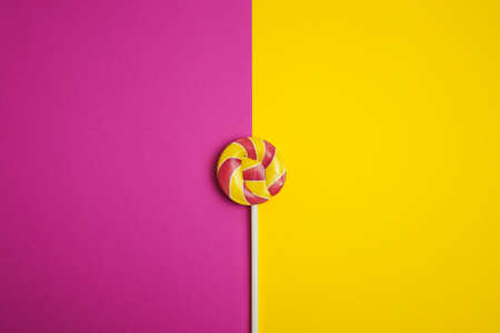 Multicolored round lollipop on yellow-pink background. valentines day.の写真素材