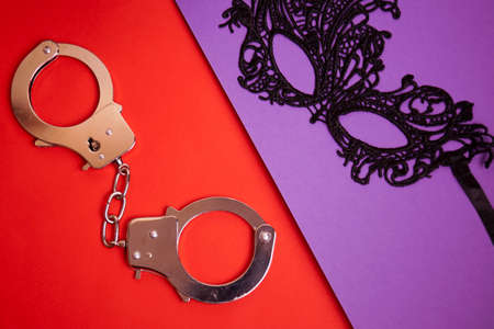 Black sexy mask, metal handcuffs on red-purple background. Role-playing games. Sex shop. valentines day.の写真素材