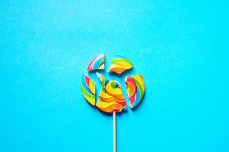 Multi-colored lollipop is divided into several parts. On a blue background. Space copy.の写真素材