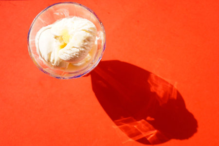 White scoops of ice cream with honey on a red background. View from above. Shadows.