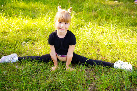 little girl in black sports uniform is engaged in fitness in nature.の写真素材
