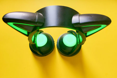 Black wireless headphones highlighted on yellow background. A cosplay accessory. Wireless gaming...
