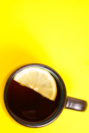 Cup of black tea on a yellow background. Lemon.の写真素材