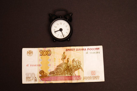 Time is money. One hundred rubles, an alarm clock on a black background.Space for text.の写真素材