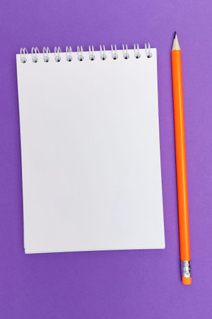 View from above. Orange pencil next to the notepad.